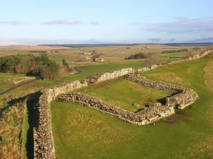 foto panorámica mostrando las ruinas en piedra del castillo y el muro, en un paisaje agrícola
