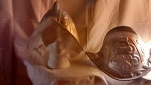 foto de dos reproducciones en plástico del tipo de casco llevado por los soldados españoles en los 1500 y 1600, con su ala (brim) curvada que sube a un punto en frente y detrás