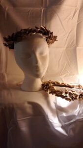 foto de dos reproducciones en plástico de coronas de hojas de laurel (laurel or bay leaves), en este caso pintadas de oro