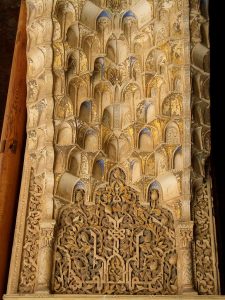 Caligrafía y elementos geométricos decorativos en la curva interior de un arco en la Alhambra de Granada. Son tallados en yeso.