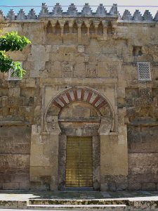 Una puerta exterior de la Mezquita de Córdoba, mostrando el arco de herradura encima de la puerta, y arcos más complejos en la cornisa arriba.