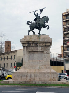 Estatua de bronce sobre un pedestal muy grande de piedra, de El Cid montado en un caballo y alzando una bandera