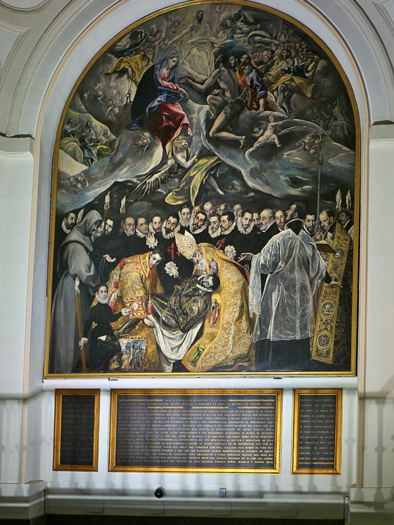 Foto de la pintura "El entierro del Conde de Orgaz" mostrando también las placas de explicación en la pared de la capilla debajo de la obra.