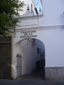 foto de un callejón con muros blancos y unas rejas puntiagudas de hierro