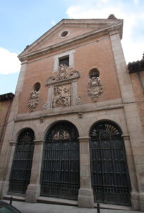 el portón del convento, de construcción en piedra y ladrillo, con rejas de hierro en las tres puertas y relieves decorativos arriba en el estilo barroco
