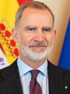 foto de Felipe VI llevando un traje oscuro, camisa azul claro y una corbata morada