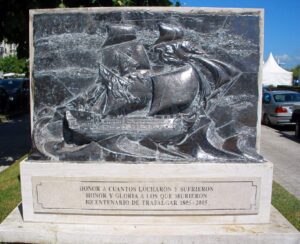 el memorial dice "Honor a cuantos lucharon y sufrieron; Honor y gloria a los que murieron; Bicentenario de Trafalgar 1805-2005" y tiene una escultura en relieve de un barco de velas entre olas grandes
