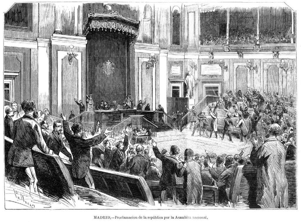 grabado que muestra gran número de diputados dándose las manos y levantando los brazos en celebración, en la gran sala de la asamblea